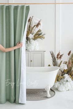 a woman standing in front of a bathtub next to flowers