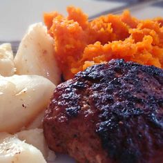 a plate with meat, potatoes and carrots sitting on top of each other in front of a fork