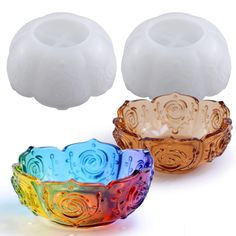 two colorful glass bowls sitting next to each other on a white surface with an object in the background