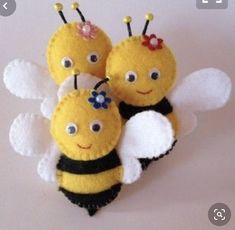 three little bees with flowers on their heads and wings are sitting next to each other