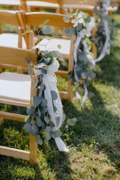 the chairs are decorated with eucalyptus leaves and ribbons