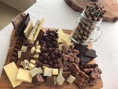 a wooden cutting board topped with lots of different types of cheeses and chocolates