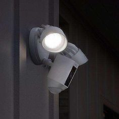 an outdoor security camera mounted on the side of a building with light coming from it