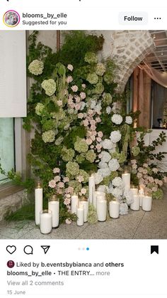 flowers and candles are arranged in front of a wall