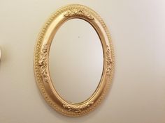 a gold oval mirror hanging on the wall