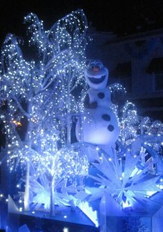 a snowman statue is lit up with christmas lights