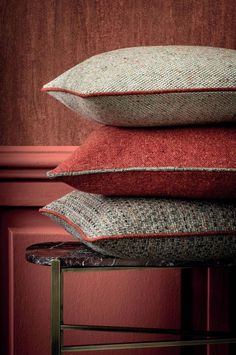 three pillows stacked on top of each other in front of a red wall and chair