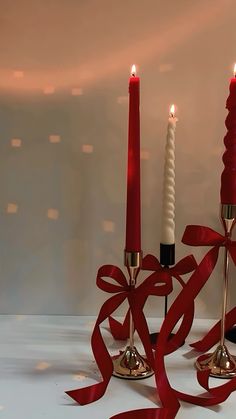 two candles with red ribbon on them sitting next to each other