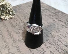 a ring sitting on top of a table next to a flower vase with flowers in it