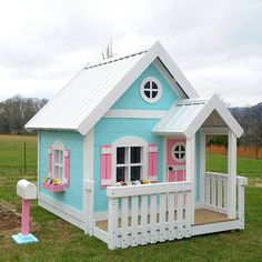 a small blue and white house with pink shutters