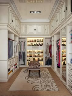 a walk in closet filled with lots of white cabinets and drawers next to a rug