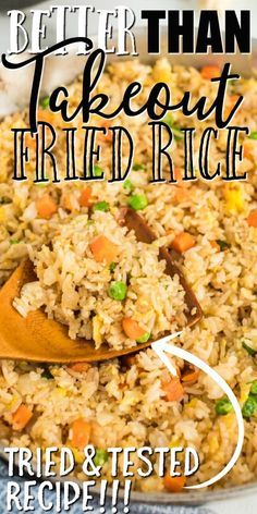 a close up of rice and carrots in a pan with a wooden spoon next to it