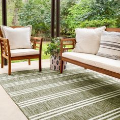 two wooden chairs sitting on top of a green rug next to a couch and chair