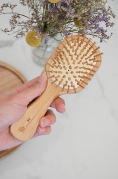 Brush your hair sustainably with our bamboo hairbrush! Made from sustainably sourced bamboo with a natural rubber cushion and bamboo pins. This little brush is gentle on tangles, helps reduce static and frizz, and comes in a convenient size that is perfect for travel, on-the-go, or kids! Care Instructions: Brush is water resistant, use on wet or dry hair. Avoid excessive water exposure to increase longevity. If the brush becomes wet, use a towel to dry and allow to air out before putting away. Over time, you may wish to oil or wax your brush to repel water. With care, it will last for years to come. Air Hole: All our brushes are designed with one bristle missing on the bottom portion of the brush. This hole provides necessary ventilation for air to escape as the pad moves. Additionally it Bamboo Hairbrush, Burgundy Bouquet, Travel Hair, Bamboo Brush, Travel Hairstyles, Laundry Decor, Wet Brush, Holiday Feast, Styling Brush