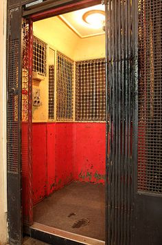 an open door to a room with red walls and bars on the wall, in front of a doorway