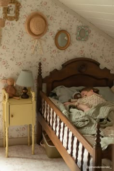 there is a small child laying in the bed with flowers on the wall behind it