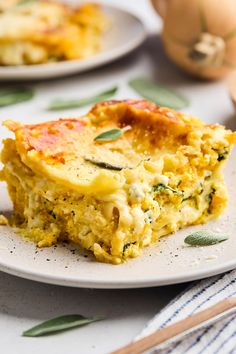 a slice of quiche with cheese and herbs on a white plate next to eggs