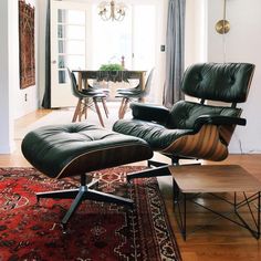 an eames chair and ottoman in the middle of a living room with a rug on the floor