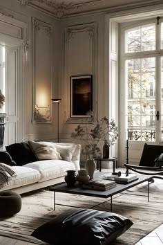 a living room filled with lots of furniture next to two large windows and white walls