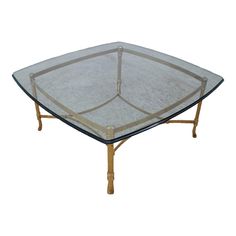 a glass and bamboo coffee table with gold trimmings on the top, against a white background