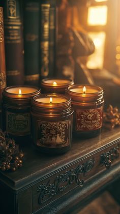 four candles sitting on top of a table next to books