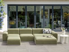 a large green couch sitting on top of a cement floor next to a white table