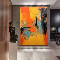 an abstract painting hangs on the wall next to a statue in a modern living room