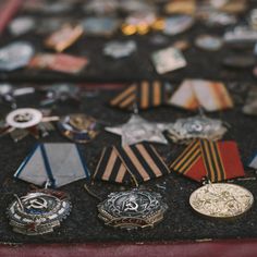 many medals and pins are on display in a red case with black velvet lining the floor