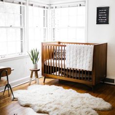 a baby's room with a crib, chair and rug on the floor