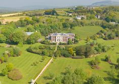 an aerial view of a large house in the middle of a lush green field with lots of trees