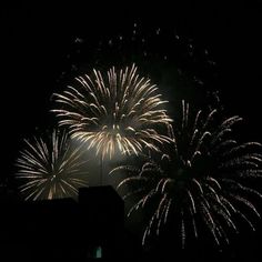 fireworks are lit up in the night sky above buildings and rooftops as seen from an apartment building