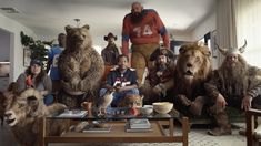 a group of people dressed in animal costumes sitting around a coffee table with stuffed animals on it