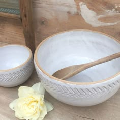 two white bowls with wooden spoons and a flower