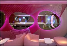 a living room filled with pink furniture and circular mirrors over the top of it's walls