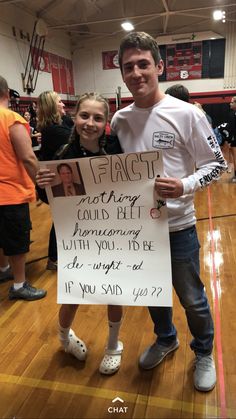 a man and woman standing next to each other in a gym holding a sign that says,