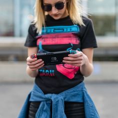 a woman in black shirt and blue skirt holding a cell phone