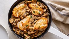 chicken with mushrooms and parsley in a skillet on top of a white table