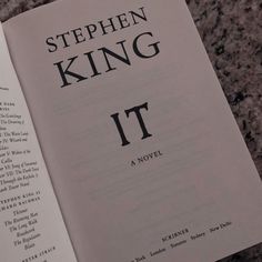 the book stephen king it is laying on top of a marble table next to an open book