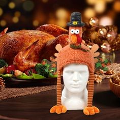 a turkey wearing a thanksgiving hat next to a white mannequin head