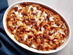 a casserole dish with pecans and cream in it on a blue cloth