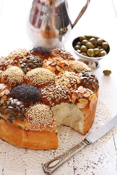 a cake with nuts on it sitting on a table next to olives and a tea pot