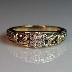 a close up of a gold ring with flowers on it and diamonds in the middle