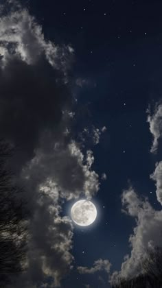 the full moon is shining brightly in the night sky with clouds and trees around it