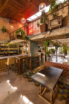 the inside of a restaurant with tables, chairs and potted plants on the wall