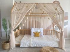 a white bed with pink drapes and pillows