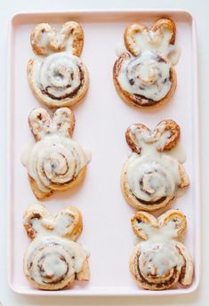 small pastries with white icing and mickey mouse ears on them in a pink tray