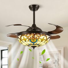 a ceiling fan with a stained glass shade hanging from it's blade blades in a living room