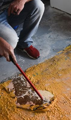 a man is using a brush to paint the floor with yellow and brown colors on it