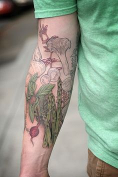 a man with a tattoo on his arm holding a radish and mushroom plant