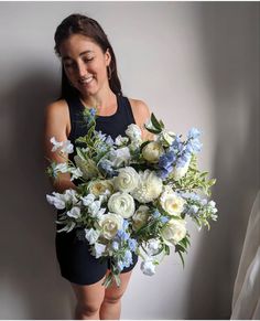 a woman holding a bouquet of white and blue flowers